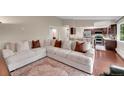 Bright and airy living room with a large white sectional couch and hardwood floors visible from the kitchen at 3450 W Amherst Ave, Denver, CO 80236