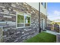 View of the side yard featuring stone and siding exterior and artificial grass at 4737 E Iliff Ave, Denver, CO 80222