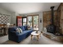 Cozy living room with a stone fireplace, a comfortable blue sofa, and views of the outdoor scenery at 29101 Drexel Spur, Evergreen, CO 80439