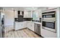 Modern kitchen with white cabinets, stainless steel appliances, stylish backsplash, and hardwood flooring at 8897 Wagner Ln, Westminster, CO 80031