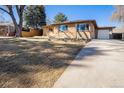 Charming brick home with driveway, large front yard, mature trees, and attached garage at 1623 S Ivy Way, Denver, CO 80224