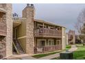Two story exterior view of condo building with balconies and a stone chimney at 3414 S Eagle St # 201, Aurora, CO 80014