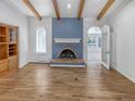 Living room with beamed vaulted ceilings, fireplace with brickwork, hardwood floors, and an archway to another room at 4365 S Alton Way, Greenwood Village, CO 80111