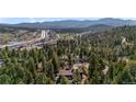 A serene aerial view of a home nestled among lush trees, with a glimpse of the town and mountains in the distance at 25531 Mosier Cir, Conifer, CO 80433