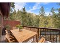 An inviting outdoor dining area on a deck with scenic views of the surrounding mountains and lush greenery at 25531 Mosier Cir, Conifer, CO 80433
