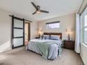 Comfortable bedroom featuring a ceiling fan, stylish sliding barn door and an en suite bathroom at 4723 Crestone Peak St, Brighton, CO 80601