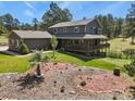Expansive property showcasing a well-maintained home with a large deck, beautifully landscaped grounds, and surrounding trees at 35550 Running Brook Ln, Elizabeth, CO 80107