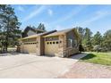Detached two car garage featuring stone accents and ample driveway space, nestled among mature trees at 35550 Running Brook Ln, Elizabeth, CO 80107