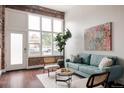 Bright living room with exposed brick, a cozy blue couch, and plenty of natural light at 1810 E 33Rd Ave, Denver, CO 80205