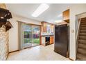 Well-lit kitchen with tile flooring, wood cabinets, black appliances, and access to the backyard at 12218 Monroe Dr, Thornton, CO 80241