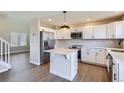 Stylish kitchen featuring white cabinets, stainless steel appliances, a center island, and sleek wood flooring at 1169 N Tabor Dr, Castle Rock, CO 80104