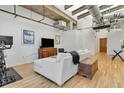 Open concept living room featuring exposed concrete ceilings, hardwood flooring and large windows at 2020 Arapahoe St # 1250, Denver, CO 80205