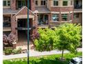 Exterior entrance of a condo building featuring lush landscaping, brickwork, and an awning at 1100 N Grant St # 208, Denver, CO 80203
