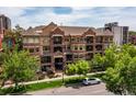 Beautiful exterior shot of a multi-story condo building with manicured landscaping and mature trees in a residential area at 1100 N Grant St # 208, Denver, CO 80203