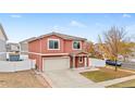 Two-story stucco home featuring an attached two-car garage, a tiled roof, and a charming covered front porch at 5552 Flanders Way, Denver, CO 80249