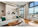 Open living room featuring hardwood floors, large windows, modern furniture, and a partial view of the kitchen at 3100 Huron St # 3E, Denver, CO 80202