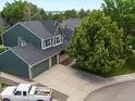 Aerial view of a green two-story house with a three-car garage, large tree and circular driveway at 8953 W Brandt Pl, Littleton, CO 80123