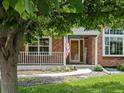 Charming brick home with a welcoming front porch, American flag, and a well-manicured lawn at 8953 W Brandt Pl, Littleton, CO 80123