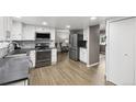 Modern kitchen with stainless steel appliances, white cabinets, stone countertops and wood flooring at 6514 Zinnia St, Arvada, CO 80004