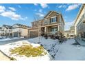 Two-story house with brown siding, snowy front yard, and attached garage at 5135 Ditmars Trl, Castle Rock, CO 80104