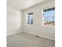 Bright bedroom with neutral carpet, white walls, and two windows allowing ample natural light at 9099 Pitkin St, Commerce City, CO 80022