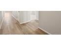 Inviting hallway with light wood-style flooring, neutral walls, and white trim at 9099 Pitkin St, Commerce City, CO 80022
