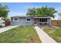Charming exterior of home with solar panels, well-maintained lawn, sidewalk, and a red front door at 3930 S Hazel Ct, Englewood, CO 80110