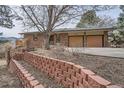 Exterior features a brick home, brick planter and mature trees in a landscaped yard at 17306 W 17Th Pl, Golden, CO 80401