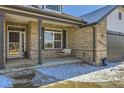 Inviting front porch featuring a swing, brick accents, and a stylish entrance door at 16650 Shadow Wood Ct, Hudson, CO 80642