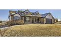 A beautiful two-story home with a brick facade, dormer windows, and a spacious front lawn at 16650 Shadow Wood Ct, Hudson, CO 80642