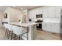 Bright kitchen featuring white cabinetry, stainless steel appliances, island seating, and modern fixtures at 6150 Sugarloaf St, Brighton, CO 80601