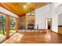 Open living room featuring a stone fireplace, wood ceilings, and scenic backyard views at 612 Nob Hill Trl, Franktown, CO 80116