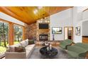 Inviting living room with stone fireplace, wood ceilings, and picturesque backyard views at 612 Nob Hill Trl, Franktown, CO 80116