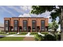 New townhome exterior showcasing brick facade, dark trim, landscaping and sidewalk access at 115 W 2Nd Ave # 104, Denver, CO 80223