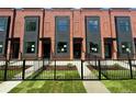 Townhome exterior shows brick facade with dark accents and manicured front yard with fence at 115 W 2Nd Ave # 104, Denver, CO 80223