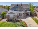 A beautiful two-story home featuring gray siding, stone accents, well manicured lawn, and a two-car garage at 4119 Riley Dr, Longmont, CO 80503