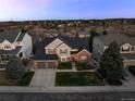 An aerial view of a charming two-story home with a three car garage, complemented by lush landscaping and a well-manicured lawn at 7862 Stonedale Dr, Castle Pines, CO 80108