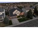 An aerial view of a charming two-story home with a three car garage, complemented by lush landscaping and a well-manicured lawn at 7862 Stonedale Dr, Castle Pines, CO 80108