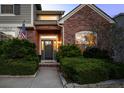 Inviting home entrance showcasing decorative bushes, brick accents, exterior lighting and a well-lit front door at 7862 Stonedale Dr, Castle Pines, CO 80108