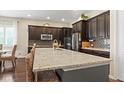 Spacious kitchen featuring a large island with granite countertops and dark wood cabinetry at 7790 S Queensburg Way, Aurora, CO 80016