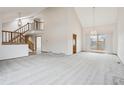 Spacious living area with vaulted ceilings, a staircase, neutral carpet, and ample natural light from large windows at 11285 Ranch Pl, Denver, CO 80234