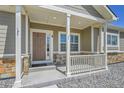 Inviting front porch featuring stone accents, white columns, and a charming front door, perfect for relaxing outdoors at 56375 E 22Nd Pl, Strasburg, CO 80136
