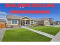 Inviting front yard with green lawn, stone accents, and a charming covered porch with seller concession in red letters at 56375 E 22Nd Pl, Strasburg, CO 80136
