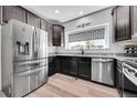 Modern kitchen features stainless steel appliances, granite counters, dark cabinets, and hardwood floors for a stylish look at 56375 E 22Nd Pl, Strasburg, CO 80136