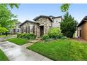 Beautiful stone house with well-maintained lawn, lush landscaping, and inviting curb appeal at 15377 W Iliff Dr, Denver, CO 80228