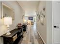 Bright hallway with wood floors, decorated walls, and a view into the living spaces at 6630 S Coolidge Ct, Aurora, CO 80016