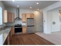 Open concept kitchen with stainless appliances, light wood cabinets, and wood laminate flooring at 8311 Parkland St, Broomfield, CO 80021