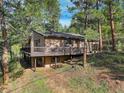 Back view of the property with a spacious deck perfect for outdoor living, surrounded by trees at 28251 Shadow Mountain Dr, Conifer, CO 80433