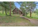Secluded wood-sided cabin nestled amongst the trees, featuring a wooden walkway leading to the main entrance at 26085 Amy Cir, Conifer, CO 80433