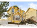 Inviting two-story yellow house, charming curb appeal, snowy landscape at 1503 S Buckley Way, Aurora, CO 80017